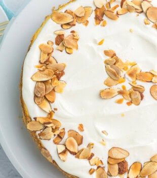 overhead view of amaretto cheesecake topped with toasted almonds on a white cake plate