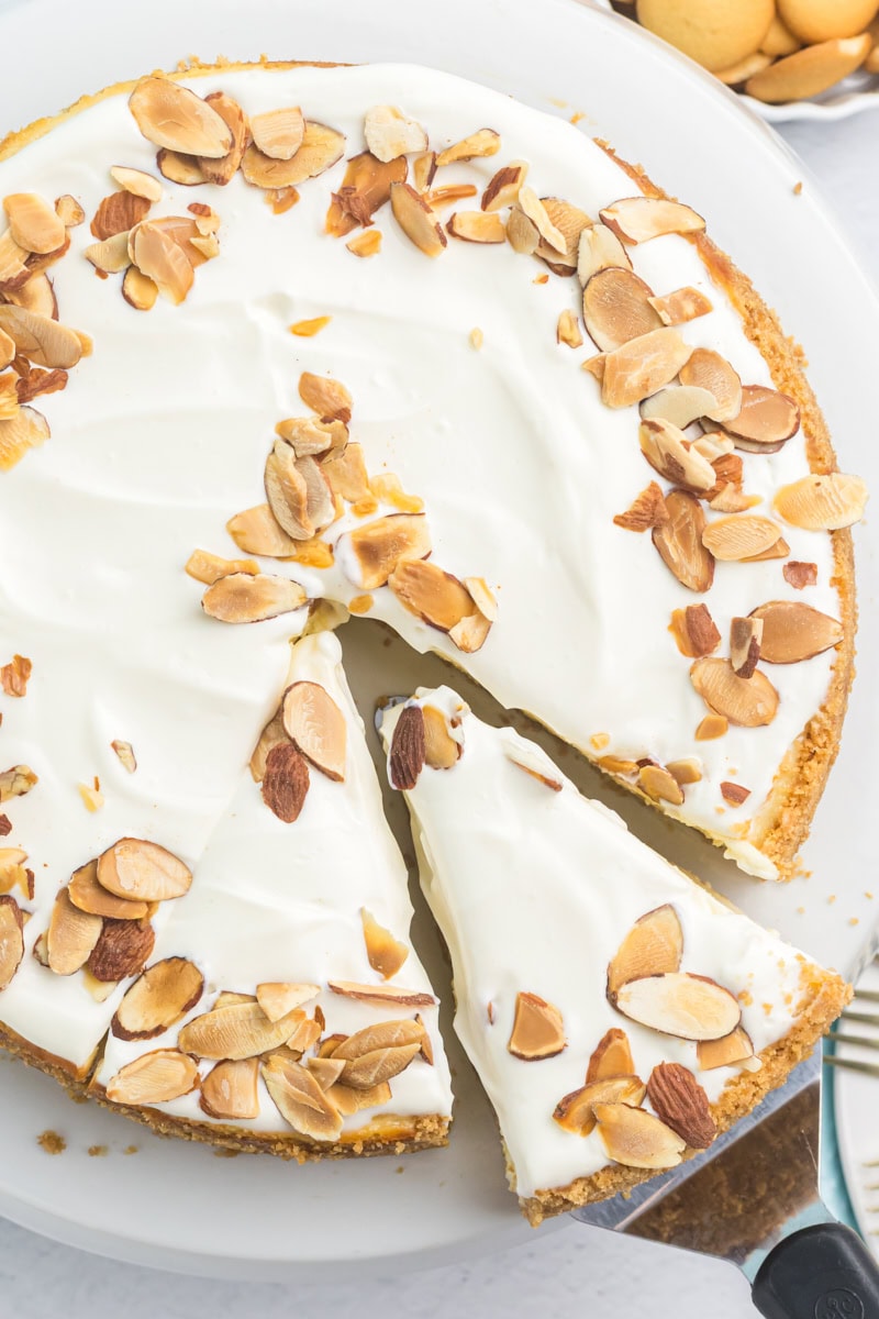 overhead view of a slice of amaretto cheesecake on a pie server being removed from the remaining cheesecake