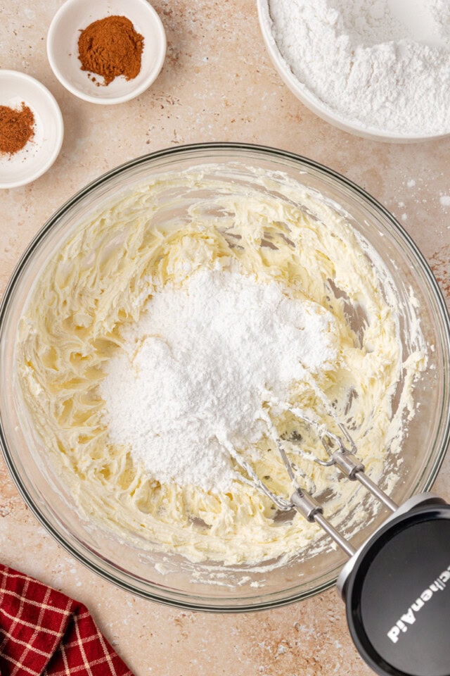 overhead view of confectioners' sugar added to creamed butter and cream cheese