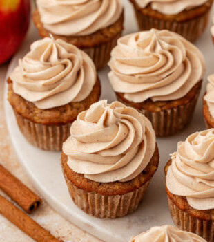 apple cupcakes topped with spiced cream cheese frosting served on a marble serving plate