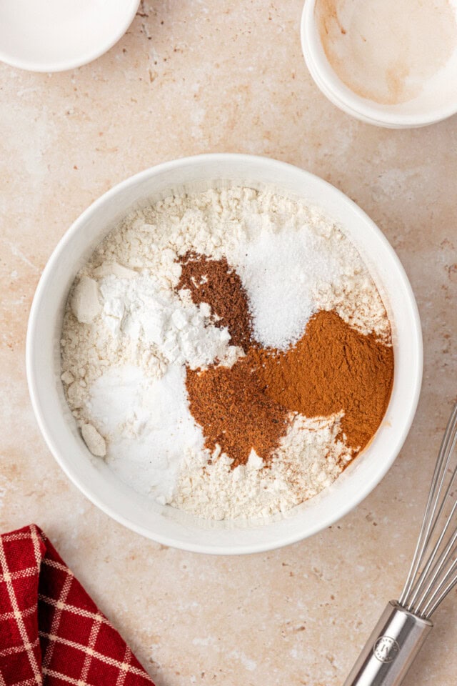 overhead view of flour, baking powder, baking soda, salt, and spices in a white mixing bowl