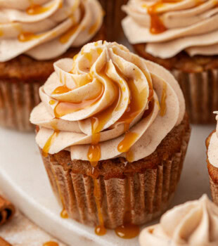 close-up of an apple cupcake topped with spiced cream cheese frosting and a drizzle of caramel