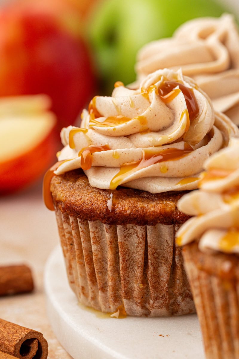 close-up of an apple cupcake on a marble tray with more cupcakes and apples surrounding