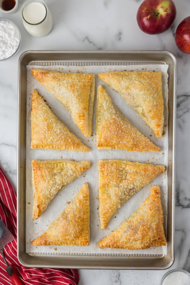 overhead view of freshly baked apple turnovers on a sheet pan