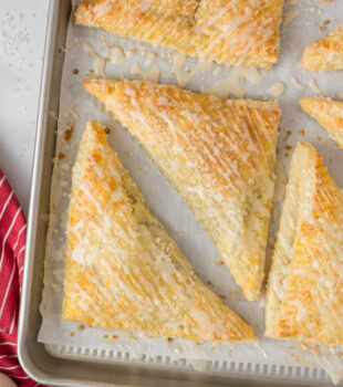 overhead view of glazed apple turnovers on a parchment-lined pan