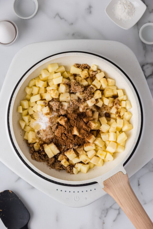 overhead view of diced apples, sugar, spices, and lemon juice in a saucepan