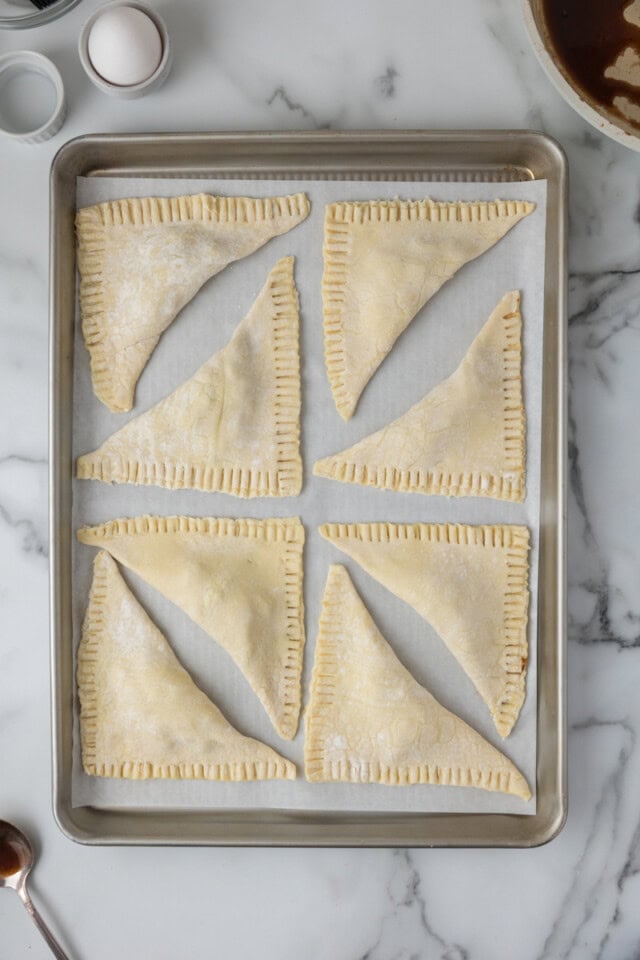 overhead view of apple turnovers on a lined baking sheet