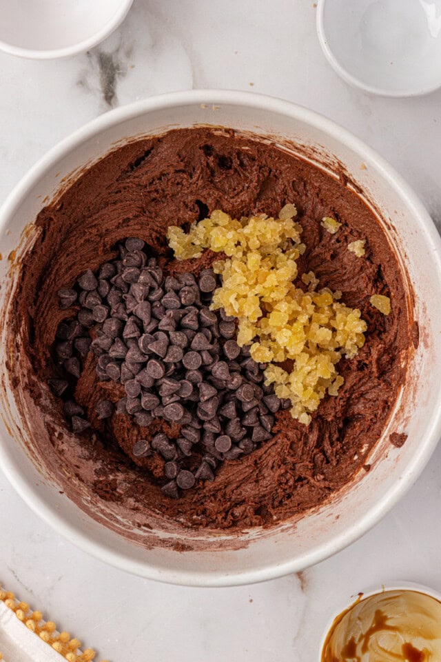 overhead view of chocolate chips and candied ginger added to chocolate cookie dough