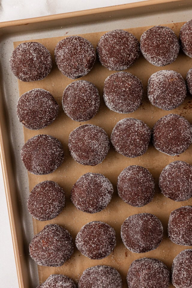 overhead view of chocolate ginger cookies scooped and rolled in sugar placed on a lined baking sheet ready to chill