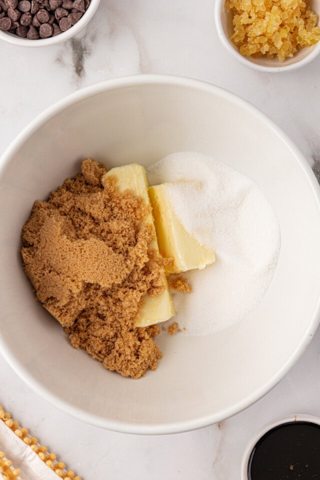 overhead view of butter, sugar, and brown sugar in a white mixing bowl