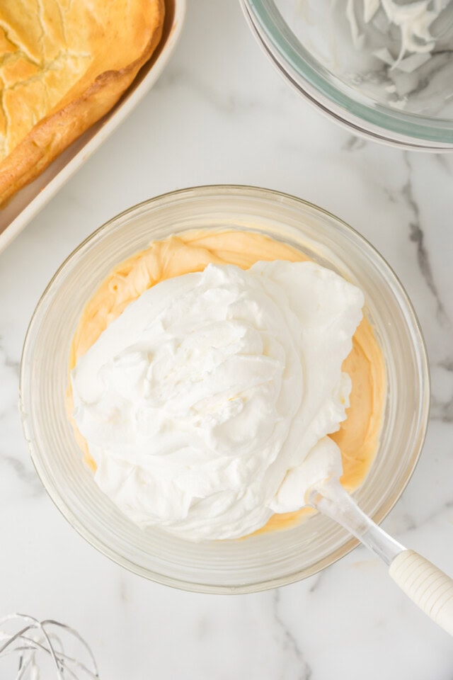 overhead view of whipped cream added to cream puff cake filling mixture