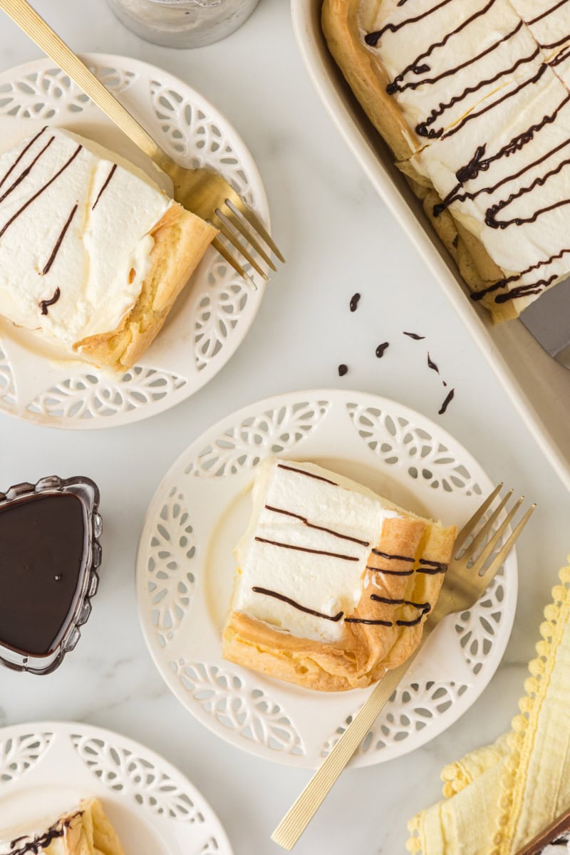 two slices of cream puff cake served on white plates with the remaining cake alongside