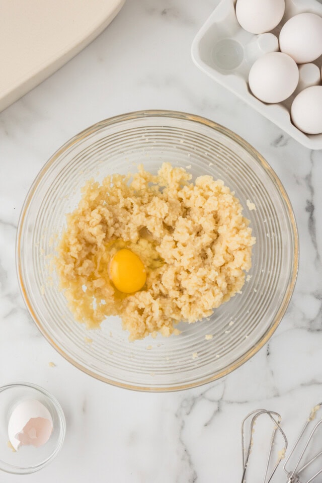 overhead view of egg added to choux pastry mixture