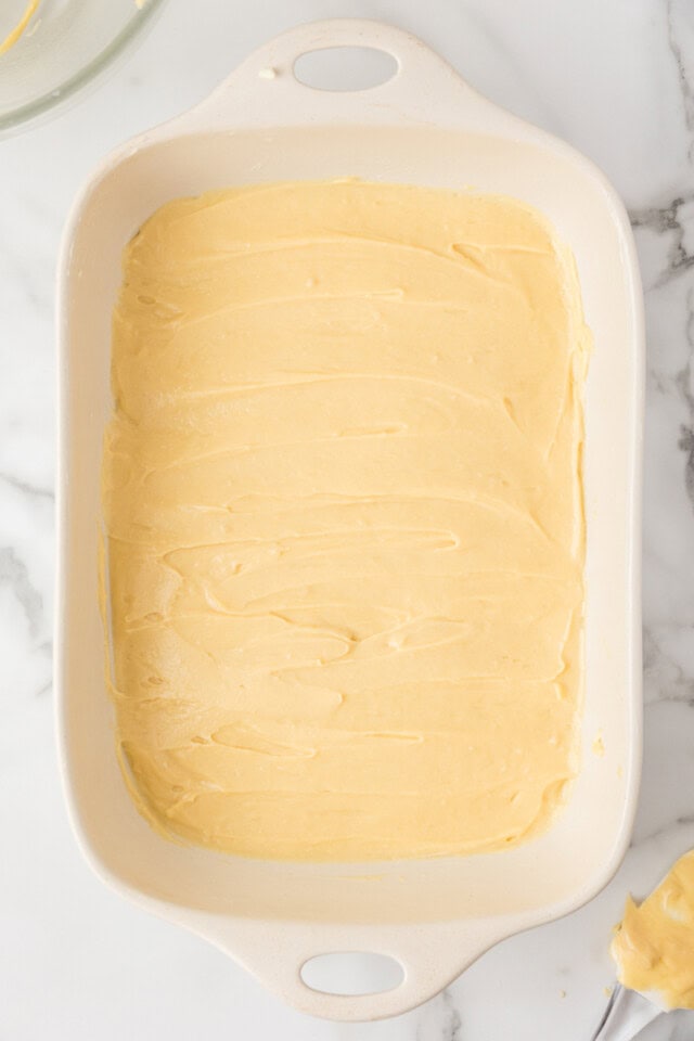 overhead view of choux pastry spread in a rectangular white pan ready to go into the oven to make the base of cream puff cake