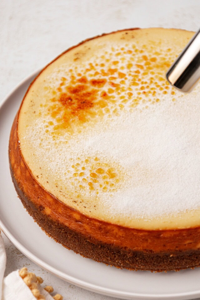 sugar topping on cheesecake being caramelized with a kitchen torch