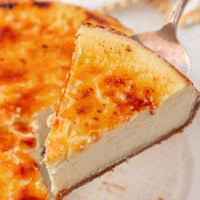a slice of crème brûlée cheesecake on a pie server with the remaining cheesecake in the background