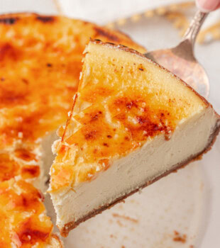 a slice of crème brûlée cheesecake on a pie server with the remaining cheesecake in the background