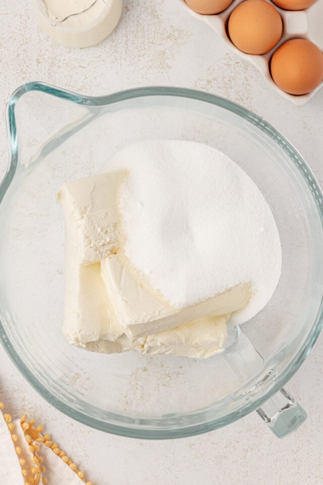 overhead view of cream cheese and sugar in a glass mixing bowl