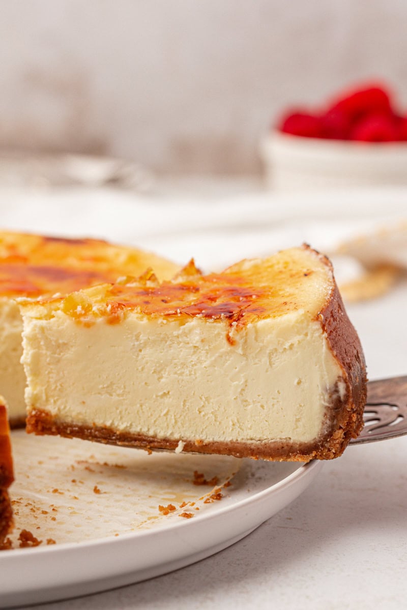a slice of crème brûlée cheesecake on a pie server being removed from the remaining cheesecake