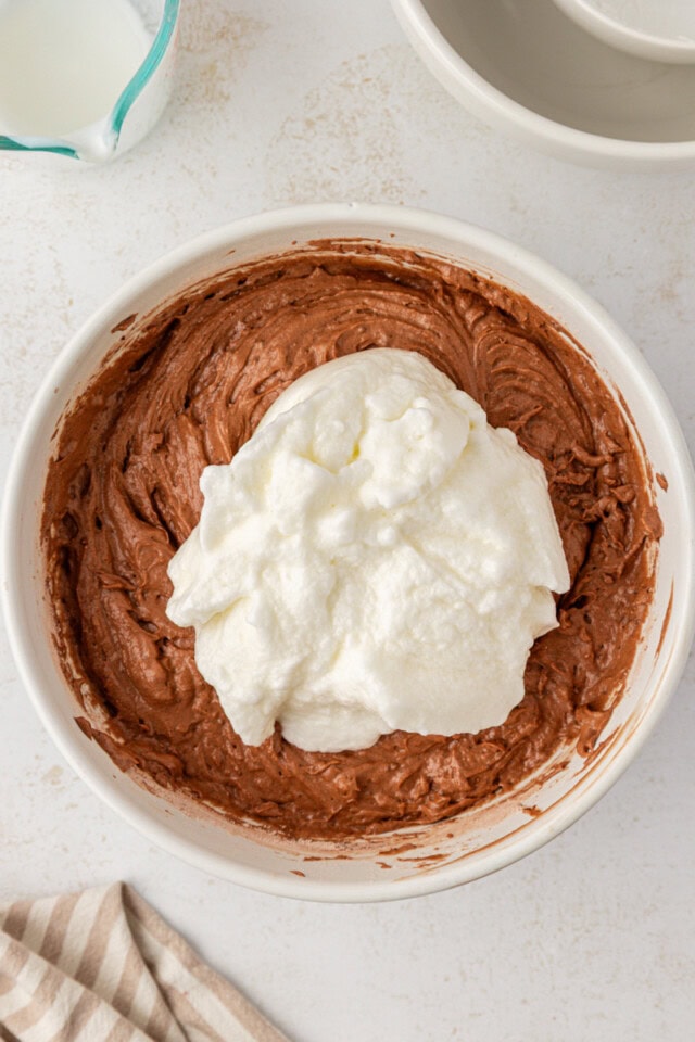 overhead view of whipped egg whites added to chocolate cake batter