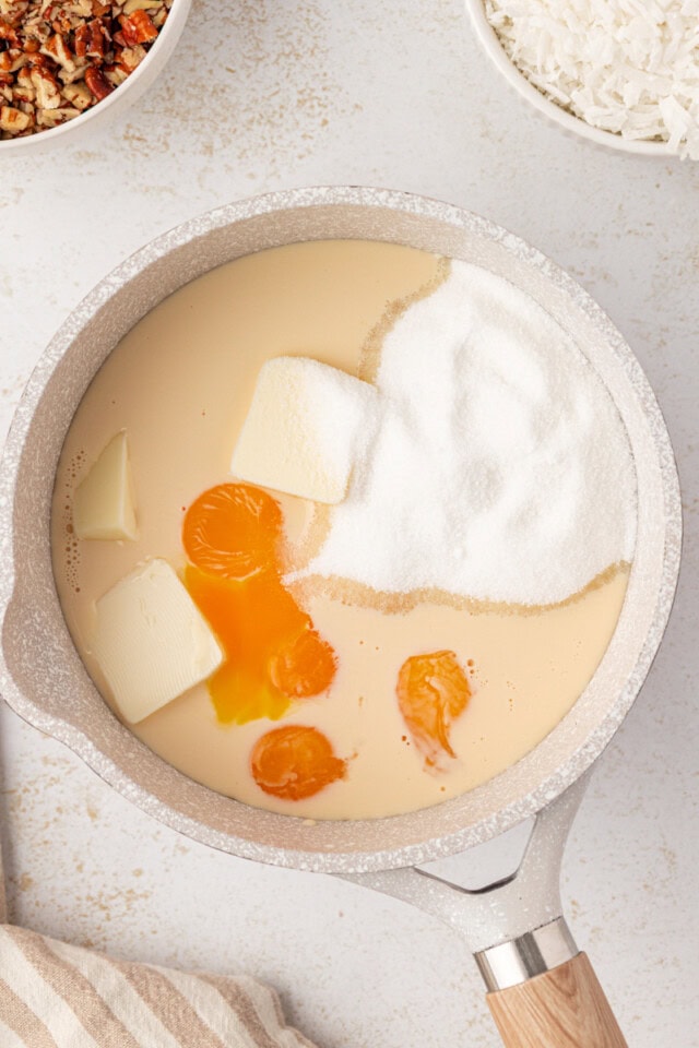 overhead view of evaporated milk, sugar, egg yolks, and butter in a saucepan