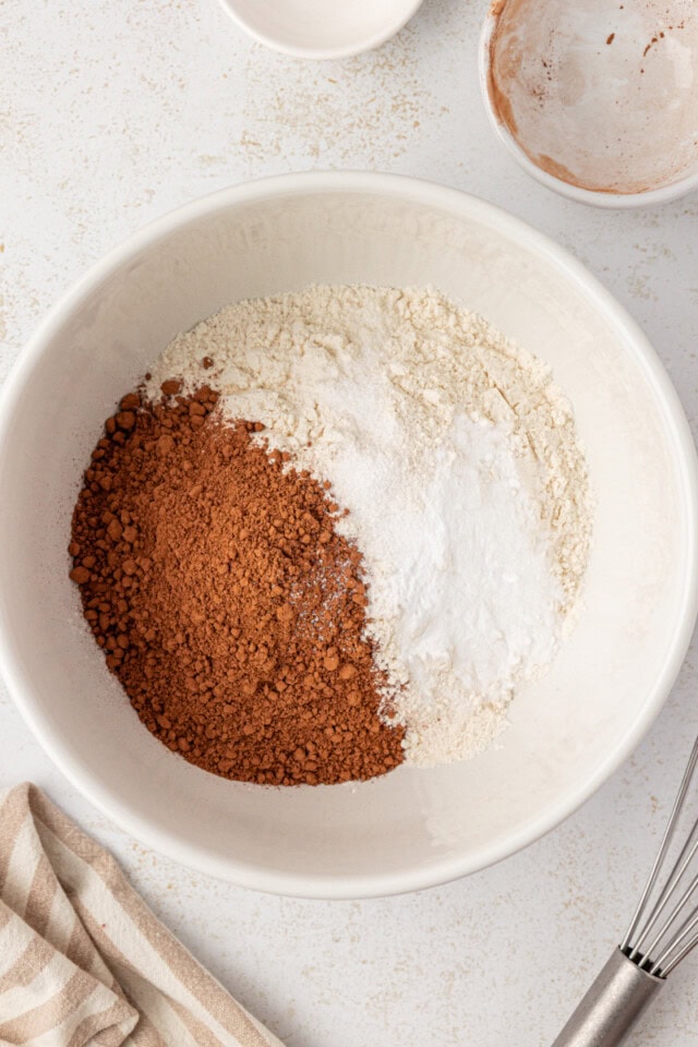 overhead view of flour, cocoa powder, baking soda, and salt in a white mixing bowl
