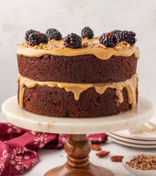 Kentucky jam cake topped with fresh blackberries and chopped nuts served on a marble cake stand