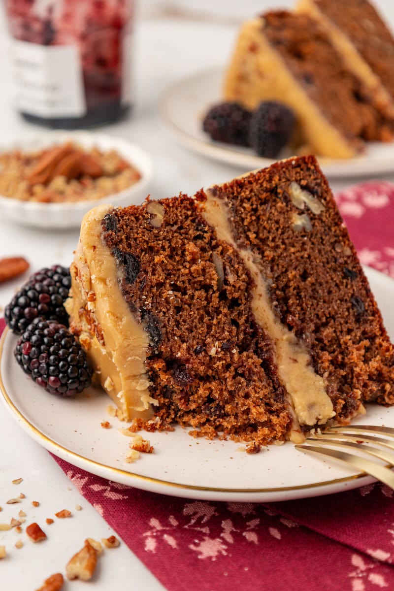 a slice of Kentucky jam cake on a white plate with a bite missing; more cake, jam, and nuts partially visible in the background