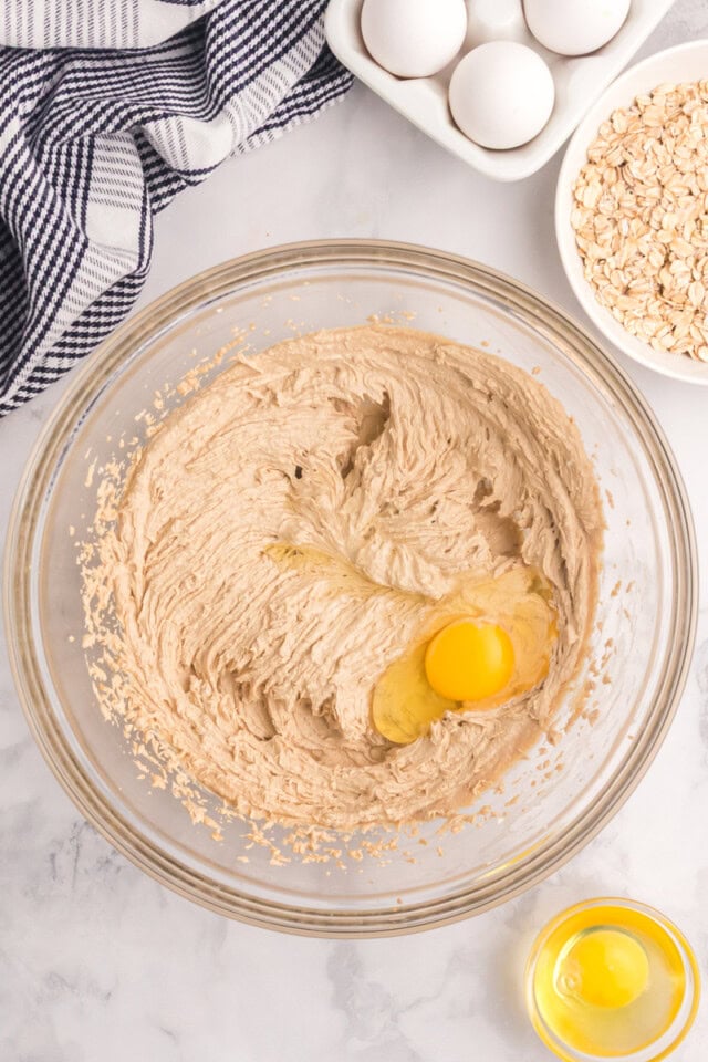 overhead view of egg added to creamed butter and sugars in a glass mixing bowl