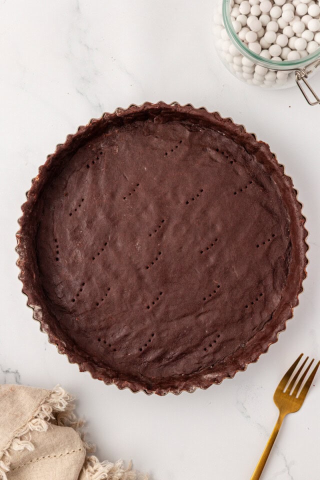 overhead view of chocolate tart dough fitted in a tart pan with a removable bottom