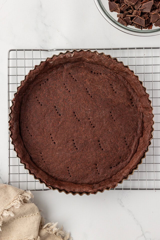 overhead view of freshly baked chocolate tart crust in a tart pan set on a wire rack