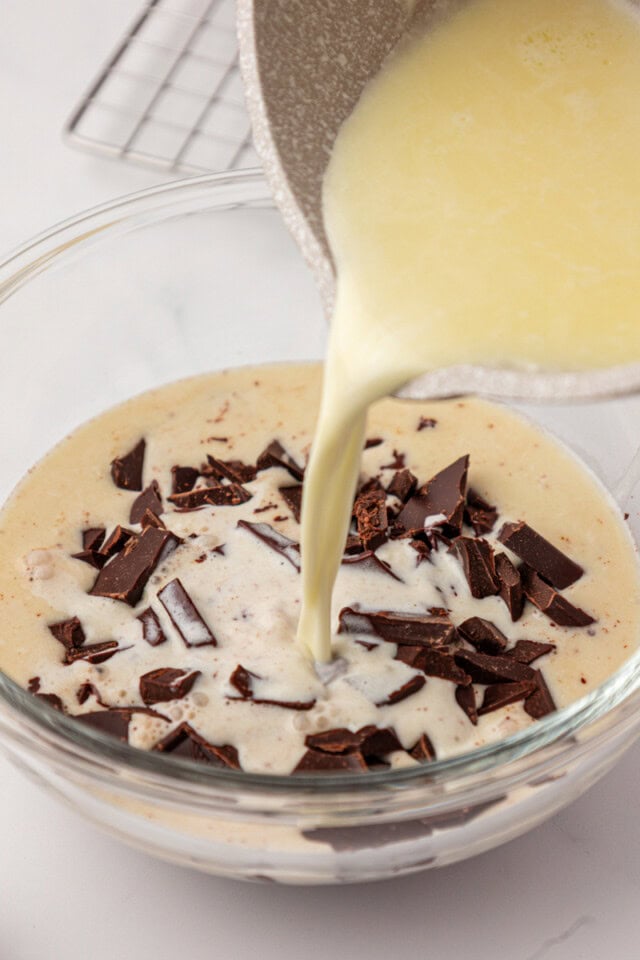 warmed cream and butter pouring over chopped dark chocolate in a glass bowl