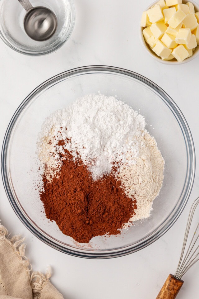 overhead view of flour, cocoa powder, confectioners' sugar, and salt in a glass mixing bowl