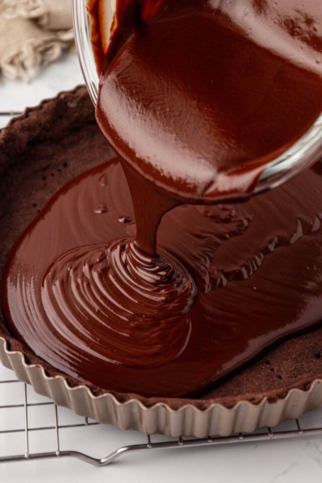 chocolate ganache pouring into a chocolate tart shell