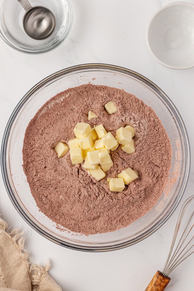 overhead view of cold cubed butter added to chocolate crust mixture
