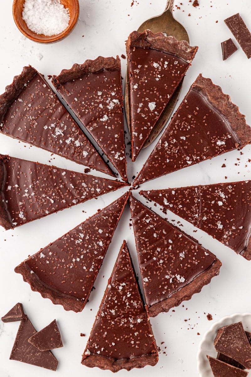 slices of salted dark chocolate tart scattered on a white surface