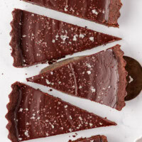 overhead view of five slices of salted dark chocolate tart on a white surface