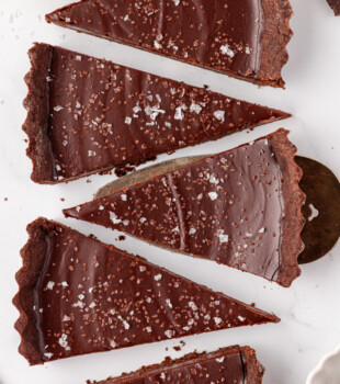 overhead view of five slices of salted dark chocolate tart on a white surface
