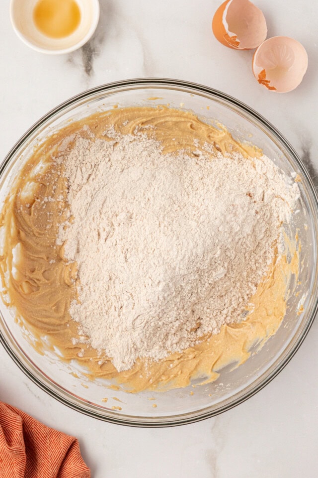 overhead view of dry ingredients added to wet ingredients for sugar and spice cookies