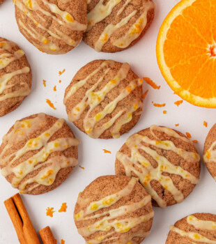 overhead view of sugar and spice cookies topped with orange glaze and scattered on a white surface