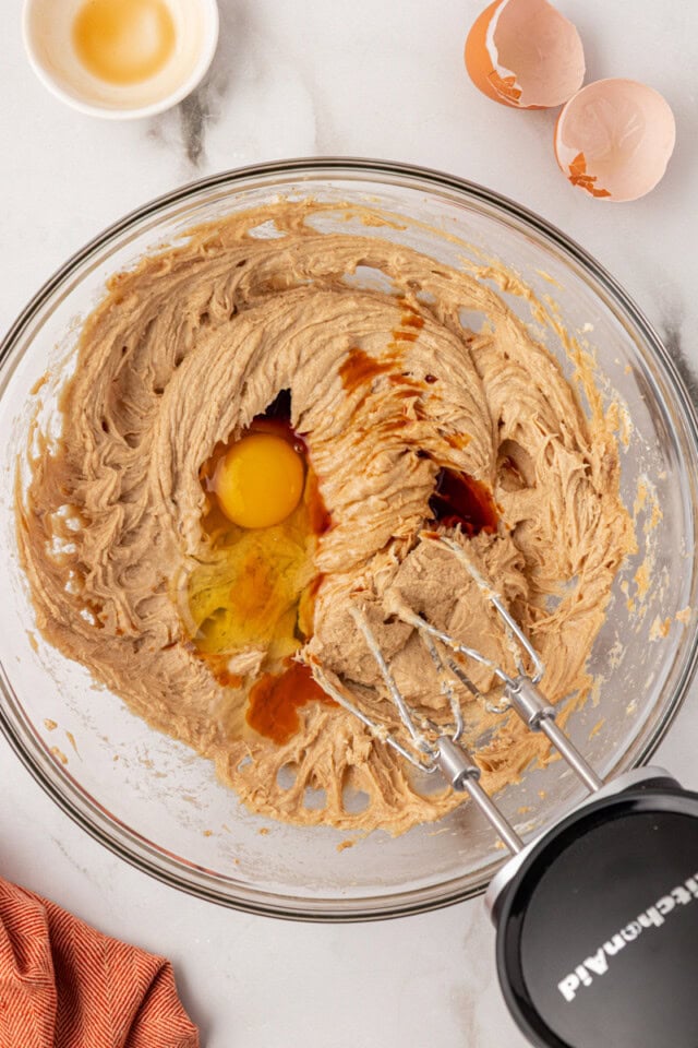 overhead view of egg and vanilla extract added to creamed butter, cream cheese, and brown sugar