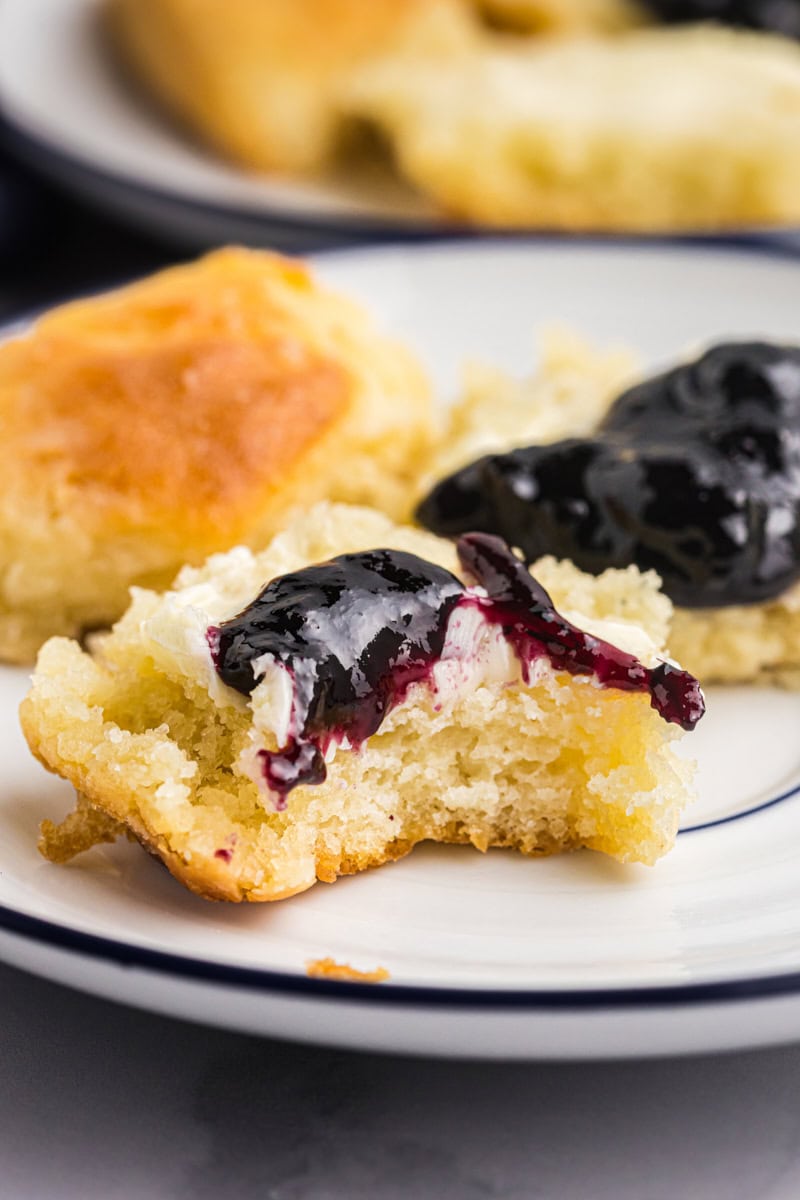 close-up of a touch of grace biscuit topped with blueberry jam, with more biscuits in the background