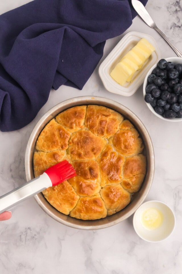 freshly baked touch of grace biscuits being brushed with melted butter