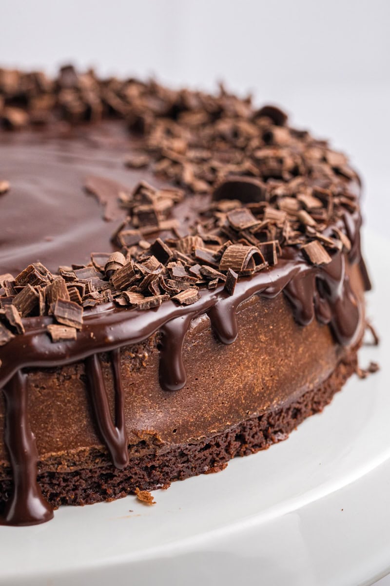 close-up of brownie bottom chocolate cheesecake on a white cake stand