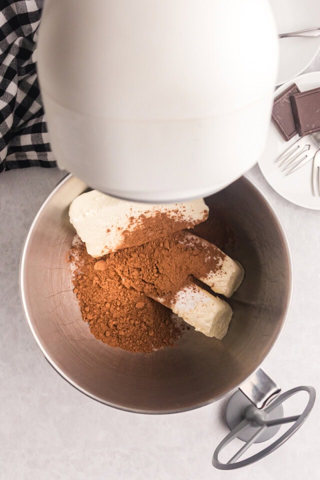 overhead view of cream cheese, sugar, and cocoa powder in the bowl of a stand mixer
