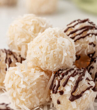 plain and chocolate-drizzled coconut snowballs on a white surface