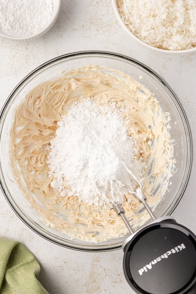 overhead view of confectioners' sugar added to cream cheese mixture for coconut snowballs