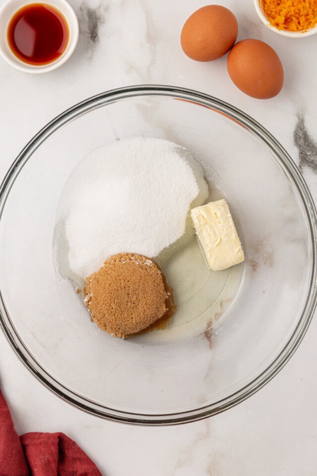 overhead view of butter, oil, sugar, and brown sugar in a glass mixing bowl