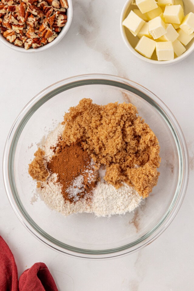 overhead view of flour, brown sugar, cinnamon, and salt in a glass mixing bowl
