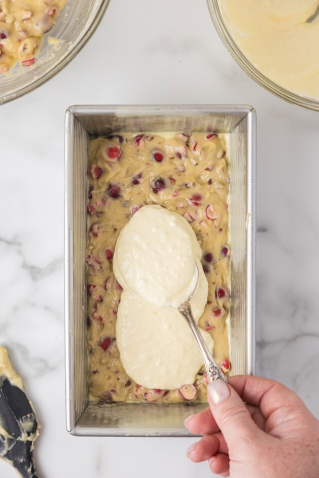 overhead view of cream cheese mixture being spread over half of the cranberry bread batter